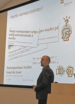 Billedet viser en person, som holder et oplg p en konference.