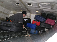 Medarbejder i lufthavn lægger bagage i fly.