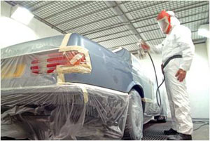 en mand med dragt og hovedbeskyttelse påfører nanocoating på en bil