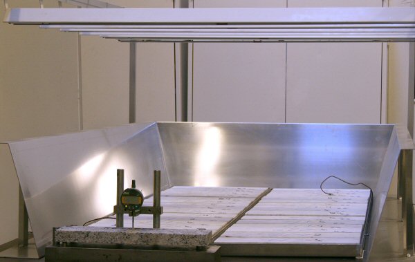 Marmorprøver placeret på vådt underlag udsat for cykliske varmepåvirkninger fra et sæt varmepaneler over prøverne.