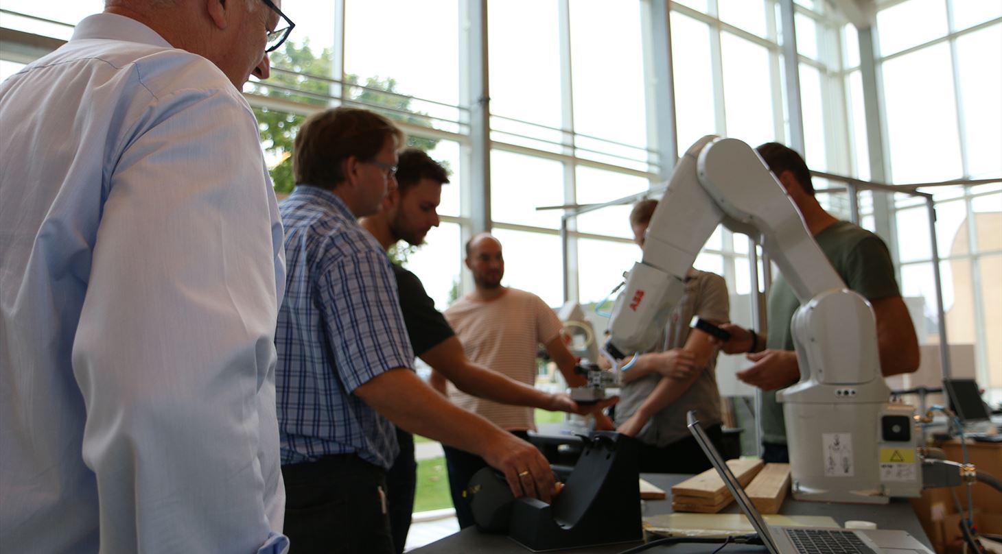 kursusdeltagere fra automationsnavigatøruddannelsen står rundt og får demonstreret en robot ved center for robotteknologi i odense