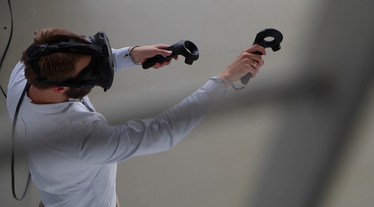 Mand har virtual reality briller på og bevæger sig med controllers i det virtuelle rum