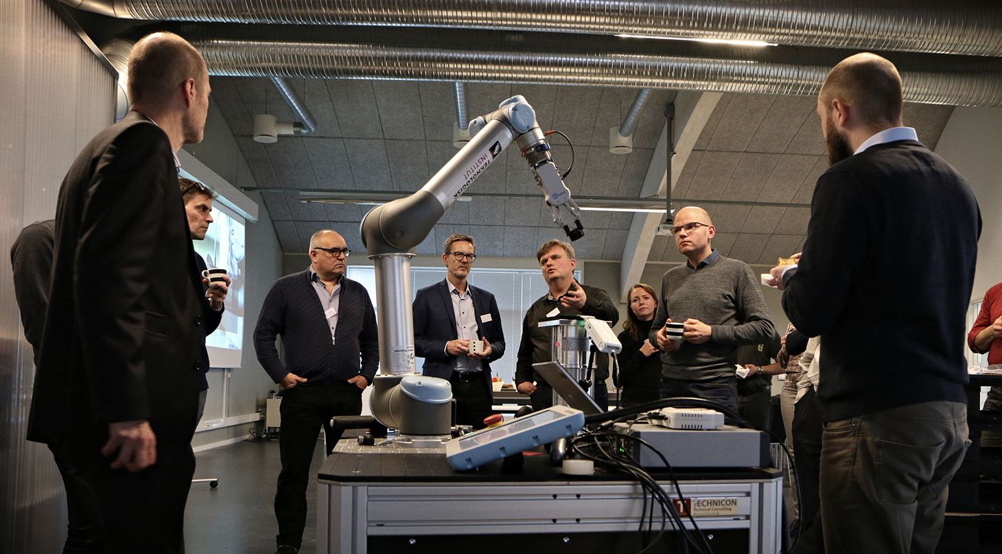 En flok mennesker står rundt om en kollaborativ robot der demonstreres