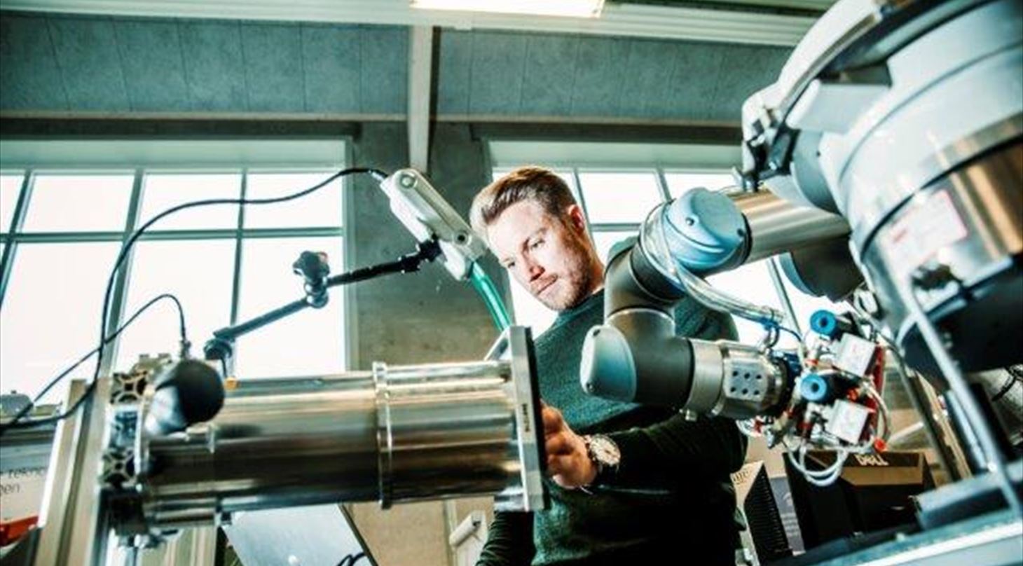 En medarbejder fra Robotcentret arbejder på en UR robot, der ses også sensor