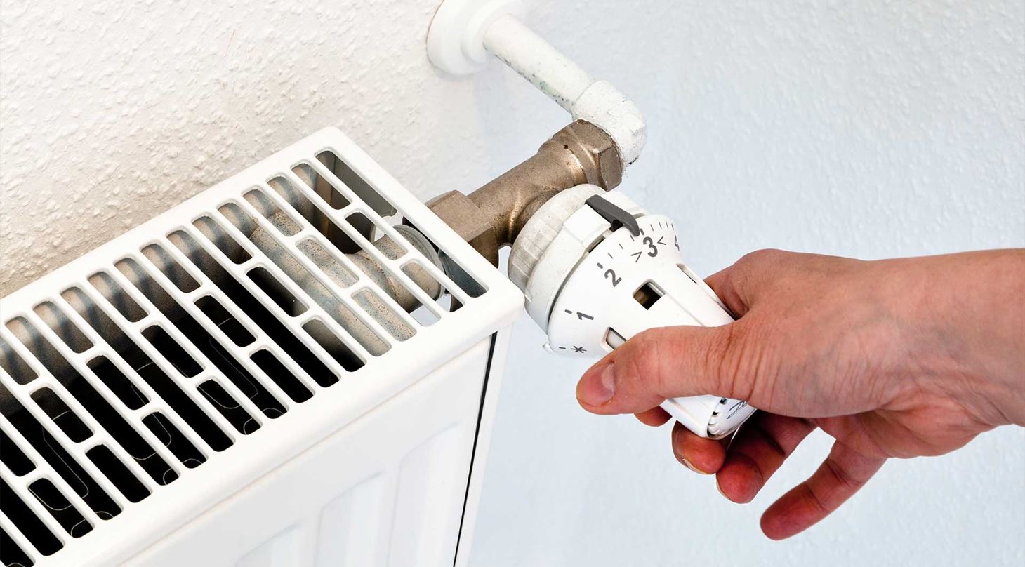 Hånd drejer på termostat på radiator