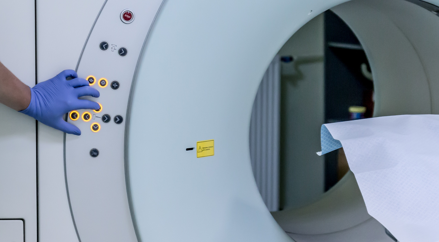 Billedet viser en hånd, der rører ved knapperne på en scanner på et sygehus.