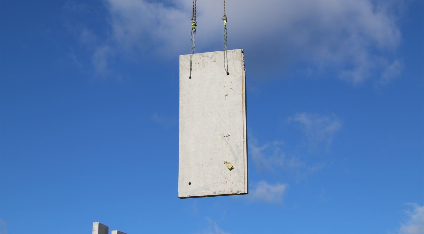 Et betonelement nedtages hel fra en eksisterende bygning med kran.