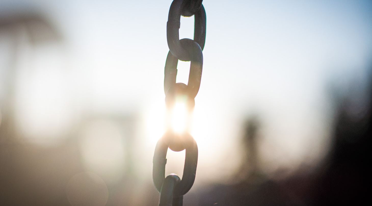 Et billede af en metalkæde med flere led i modlys.