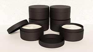 Billedet viser seks sorte emballager til creme fremstillet af Coastgrass af ålegræsmateriale. Emballagerne på billedet er ikke de endelige emballager.