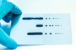 Billedet viser en prve med en oleofob, olieafvisende coating p aluminium. Billedet viser tydeligt, hvordan olien perler af p den coatede halvdel. Billedet er brugt i Plast og Emballages Medlemsinformation nr. 4-2024