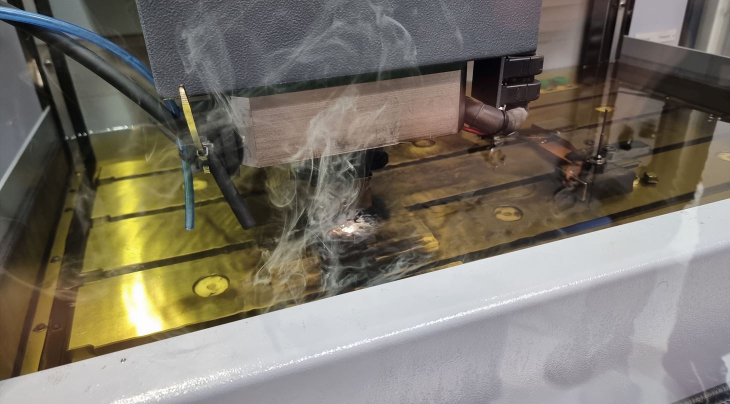 En CNC-maskine bearbejder metal med gnister og r�g under processen.