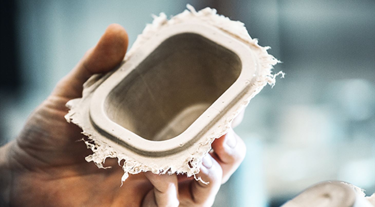 Billedet viser en hnd, der holder en papiremballage taget direkte fra formen. Billedet er bragt i Plast og Emballages Medlemsinformation nr. 2-2025