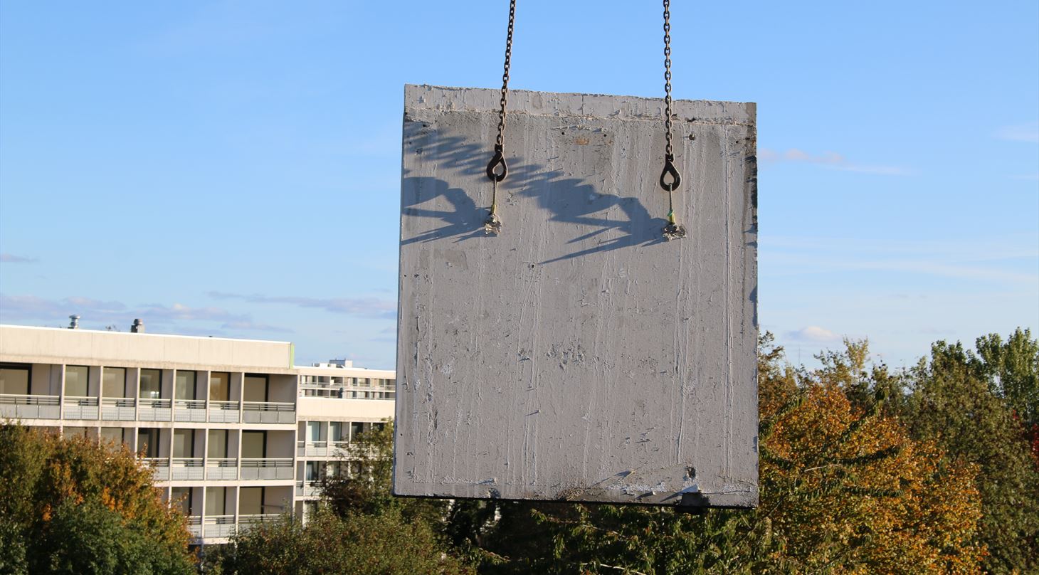Billedet viser et betonelementet, som lftes ud af en bygning med kran.
