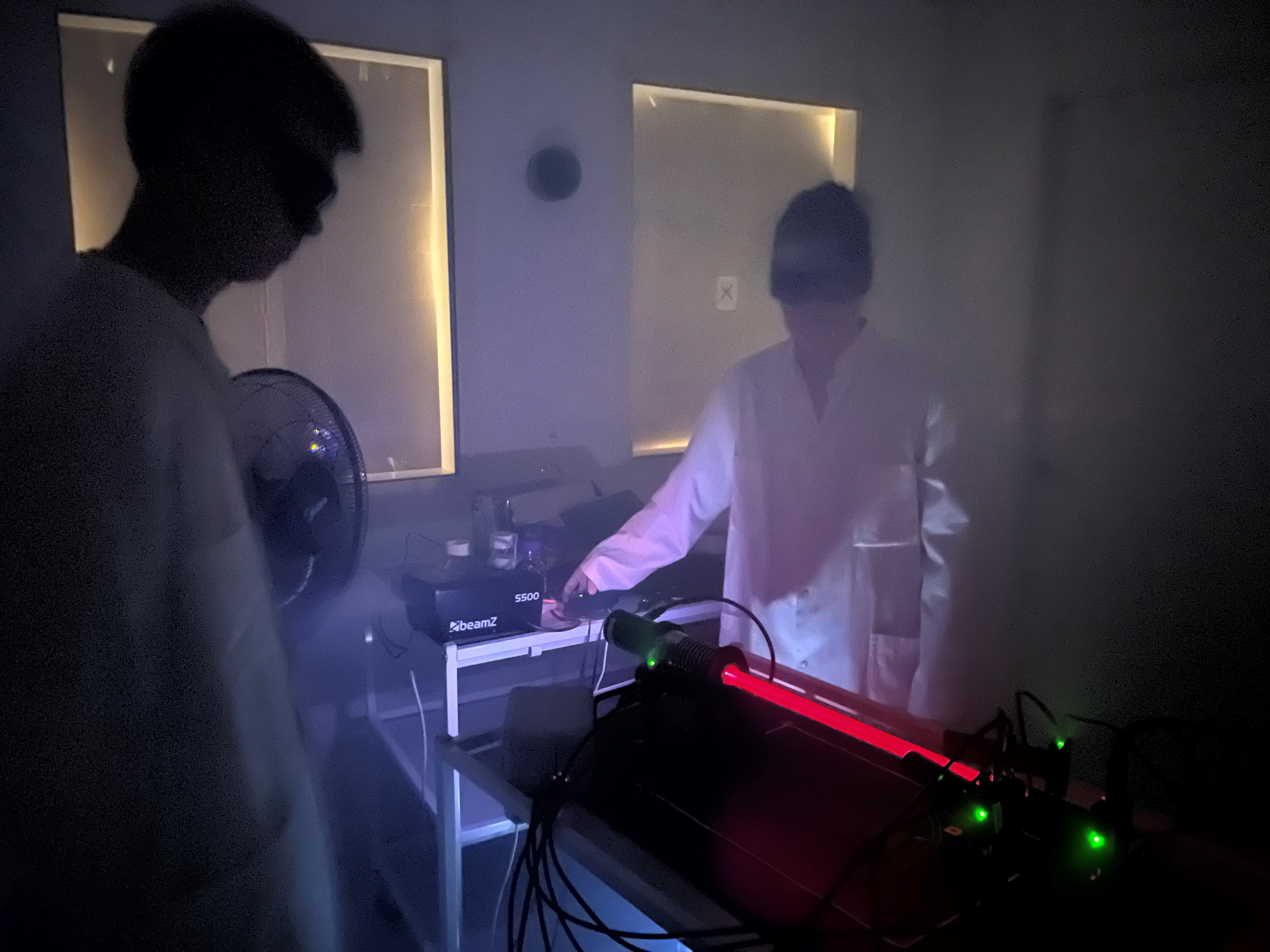 Laserstrle i mrkt rum med to specialister som str med udstyr til at mle black carbon