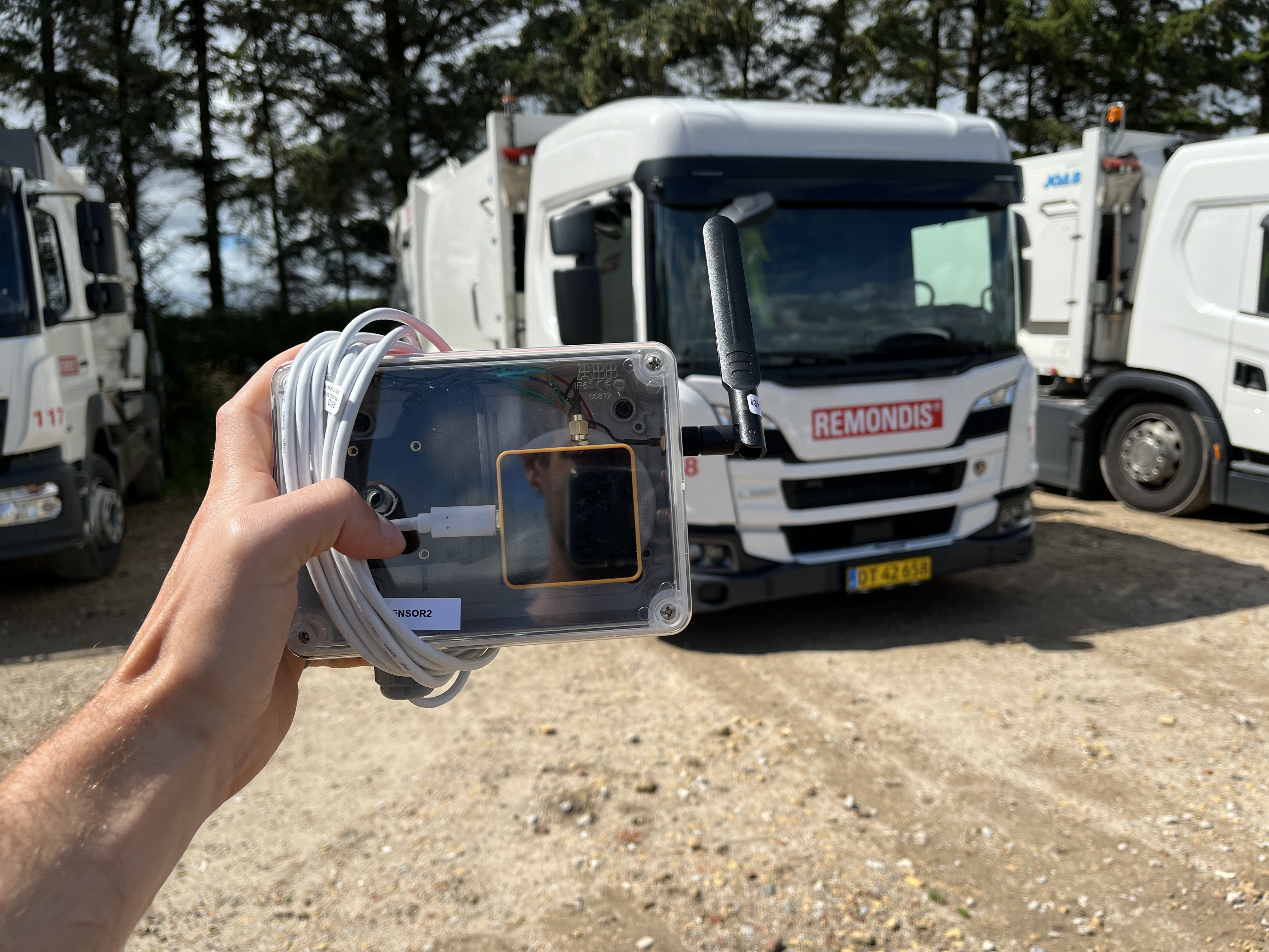 Hnd der holder en luftmler foran en skraldebil