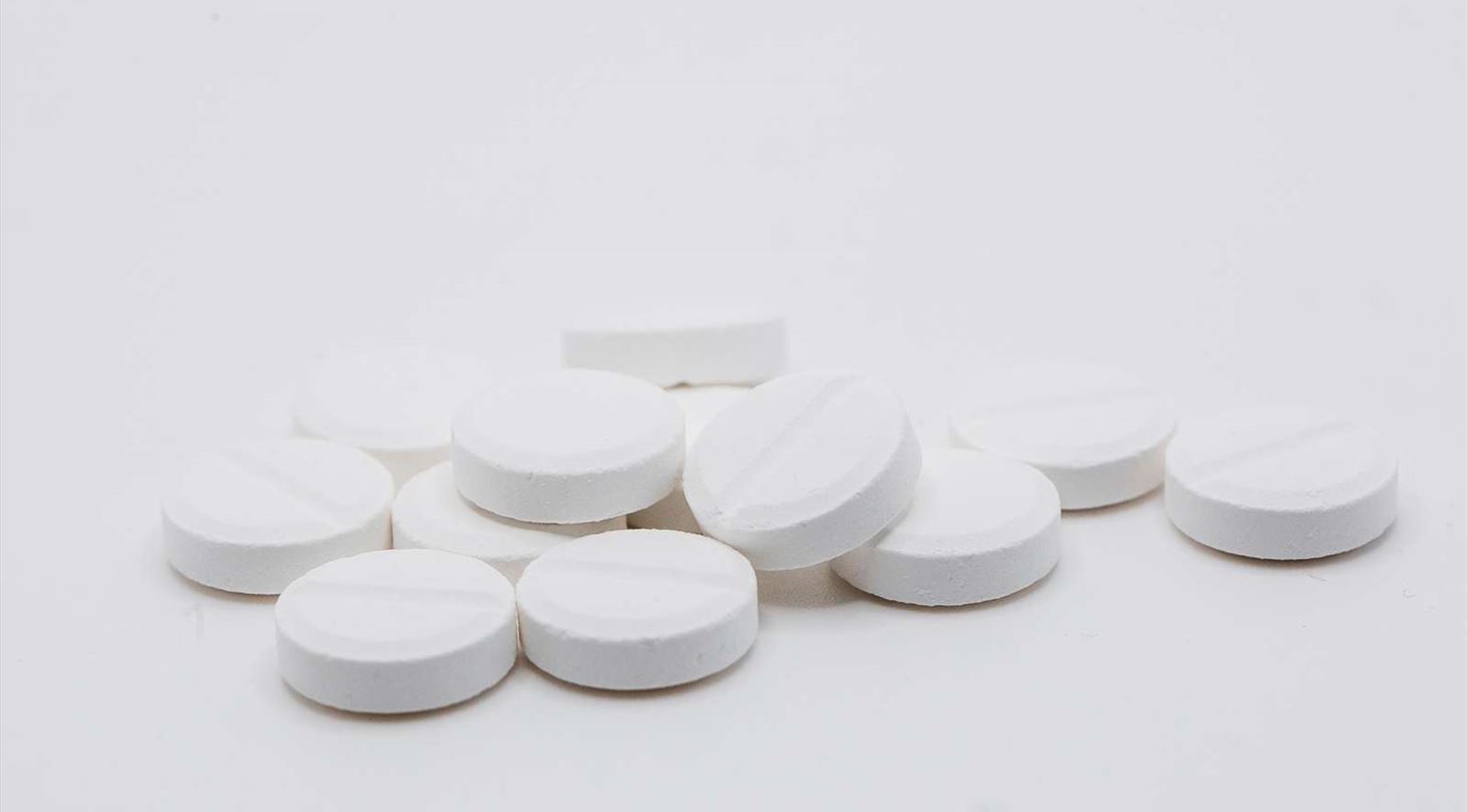 En håndfuld piller ligger på en hvid baggrund
