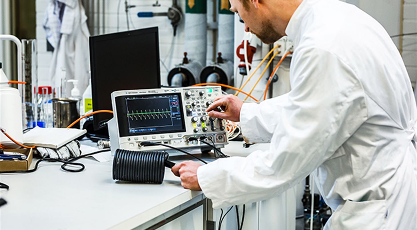 Billedet viser en laboratoriesituation med en man, der st�r ved m�leapparater