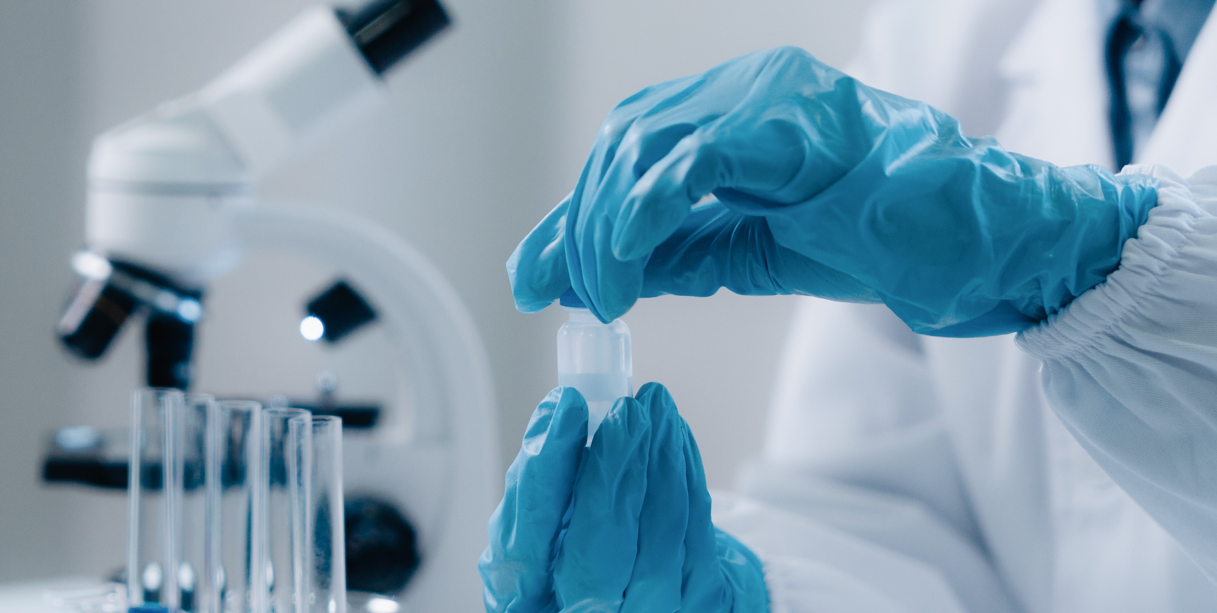 Handsker i et laboratorie der holder en farmabeholder