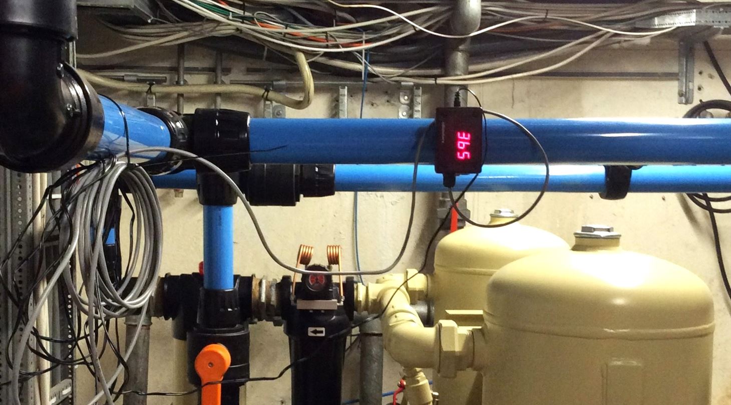 Industriel trykluftinstallation med bl� r�r, beige beholdertanke og en monteret digital sensor med et r�dt LED-display til datam�ling